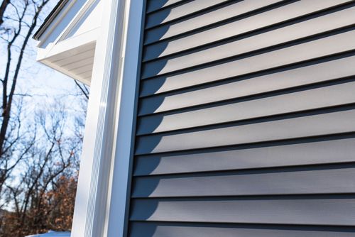 Close-up of blue-gray house siding and white trim against a winter sky