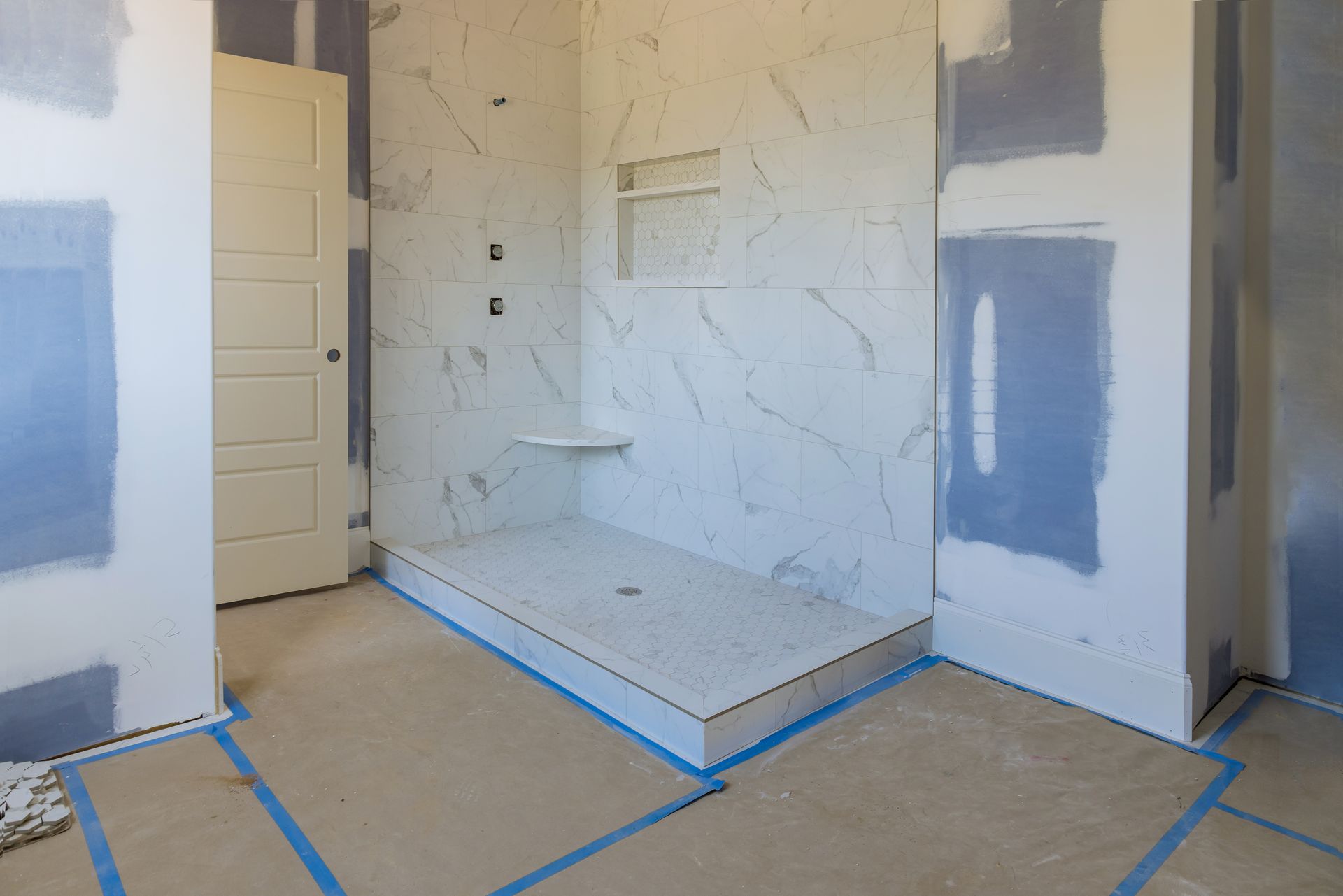 Unfinished room with taped drywall, a small raised platform, and a partially open door.