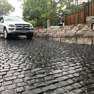 Precast cobble stone driveway with large natural stone retaining wall