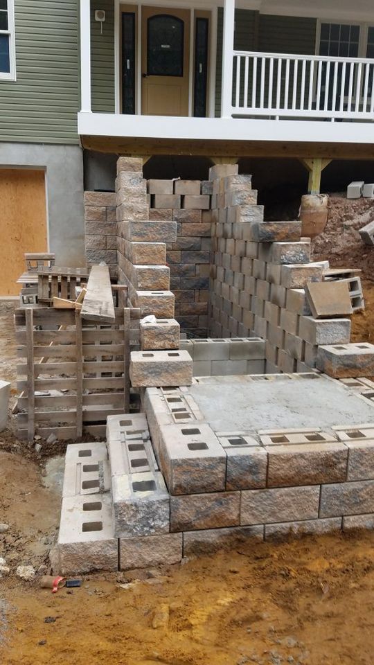 Construction of stone steps leading to a porch. The steps are brown and tan, set into a dirt landscape.