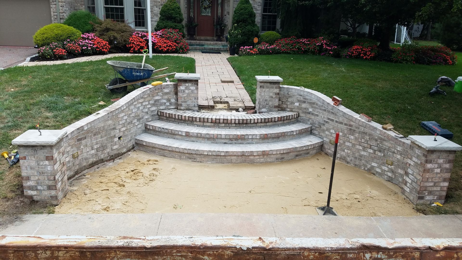 Brick steps and retaining walls under construction, leading to a house entrance.