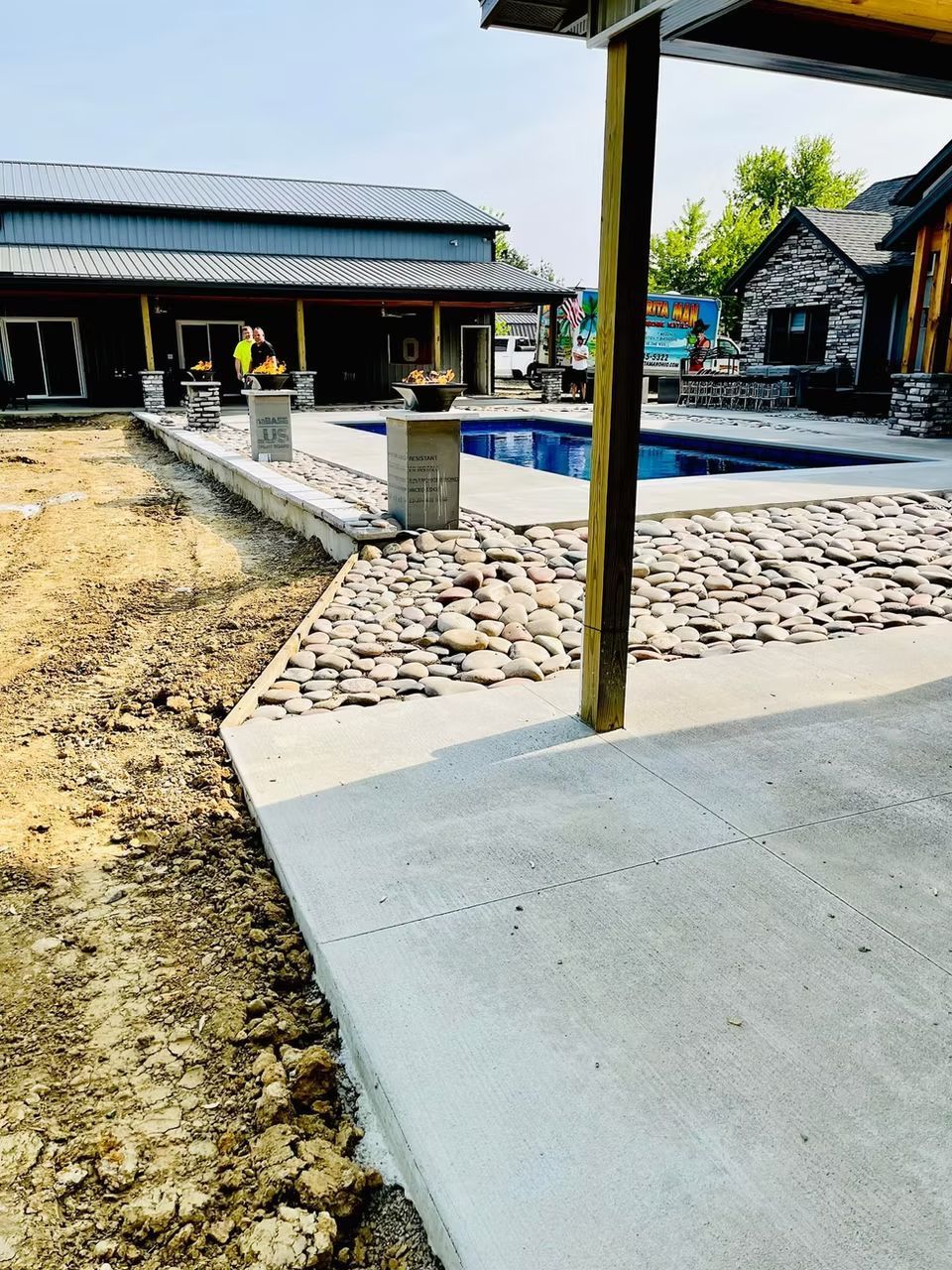 Outdoor patio with a pool, stone walkway, and covered buildings in bright sunlight