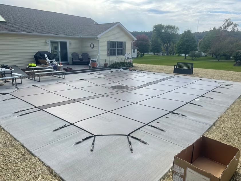 Grid of black-framed panels laid out on a patio in a backyard beside a house