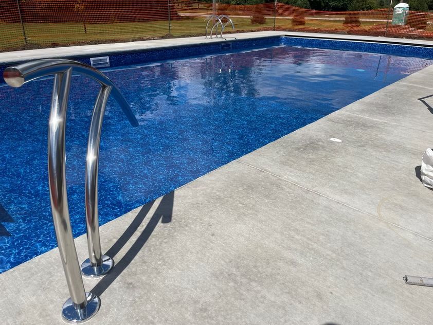 Swimming pool with stainless steel handrails beside a concrete deck