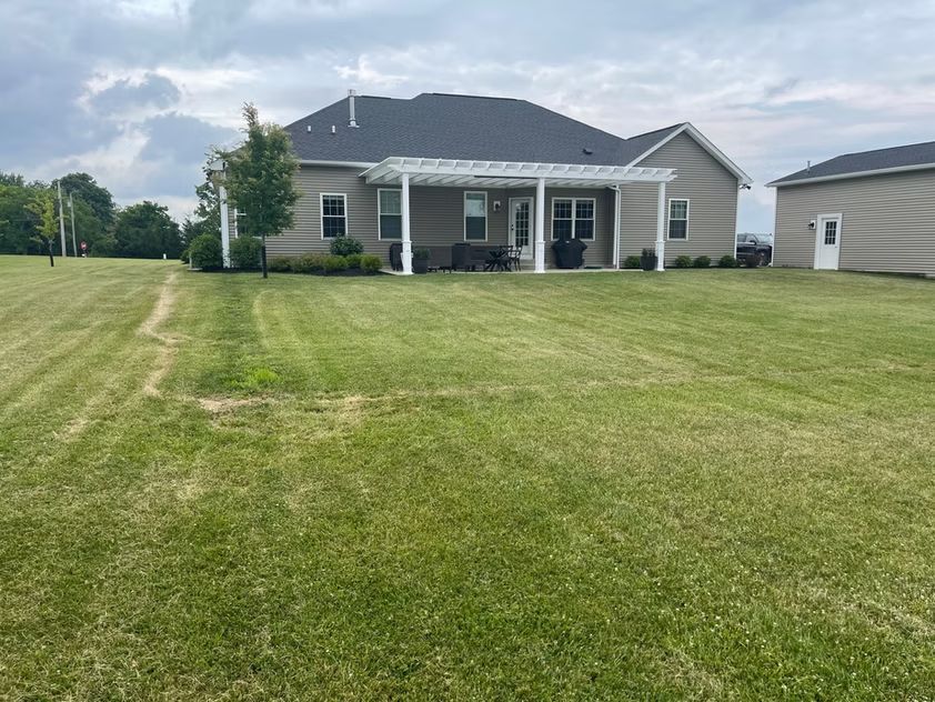 Suburban house with a large green lawn and covered front porch under cloudy skies