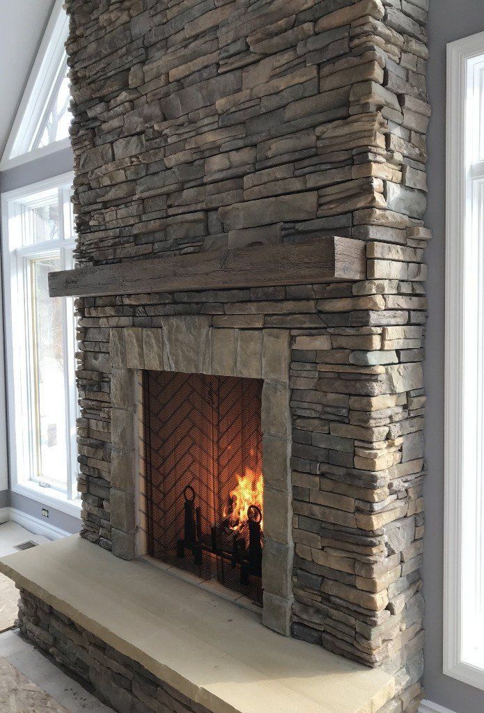 A large stone fireplace in a living room with a wooden mantle.