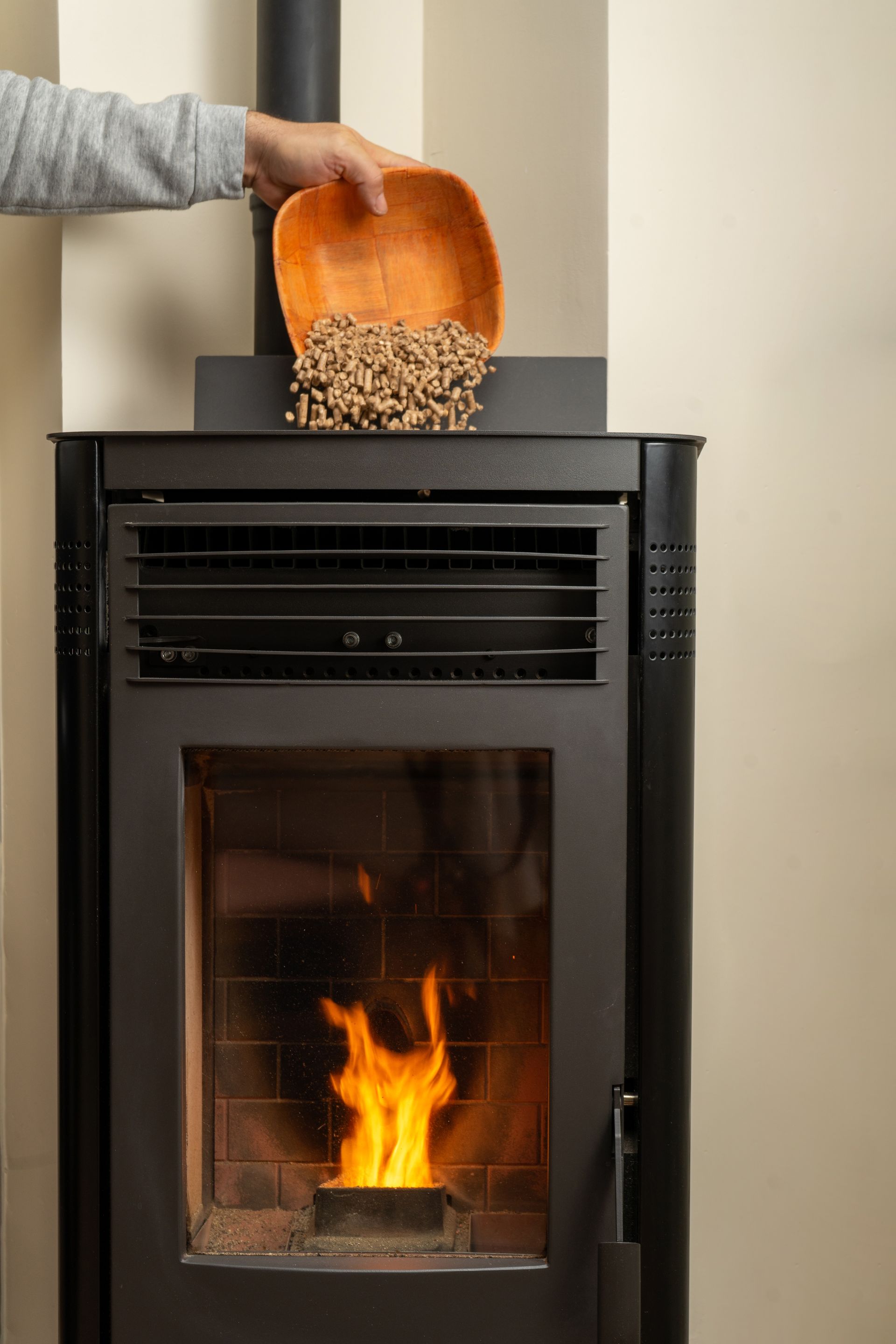 A person is pouring wood pellets into a pellet stove.