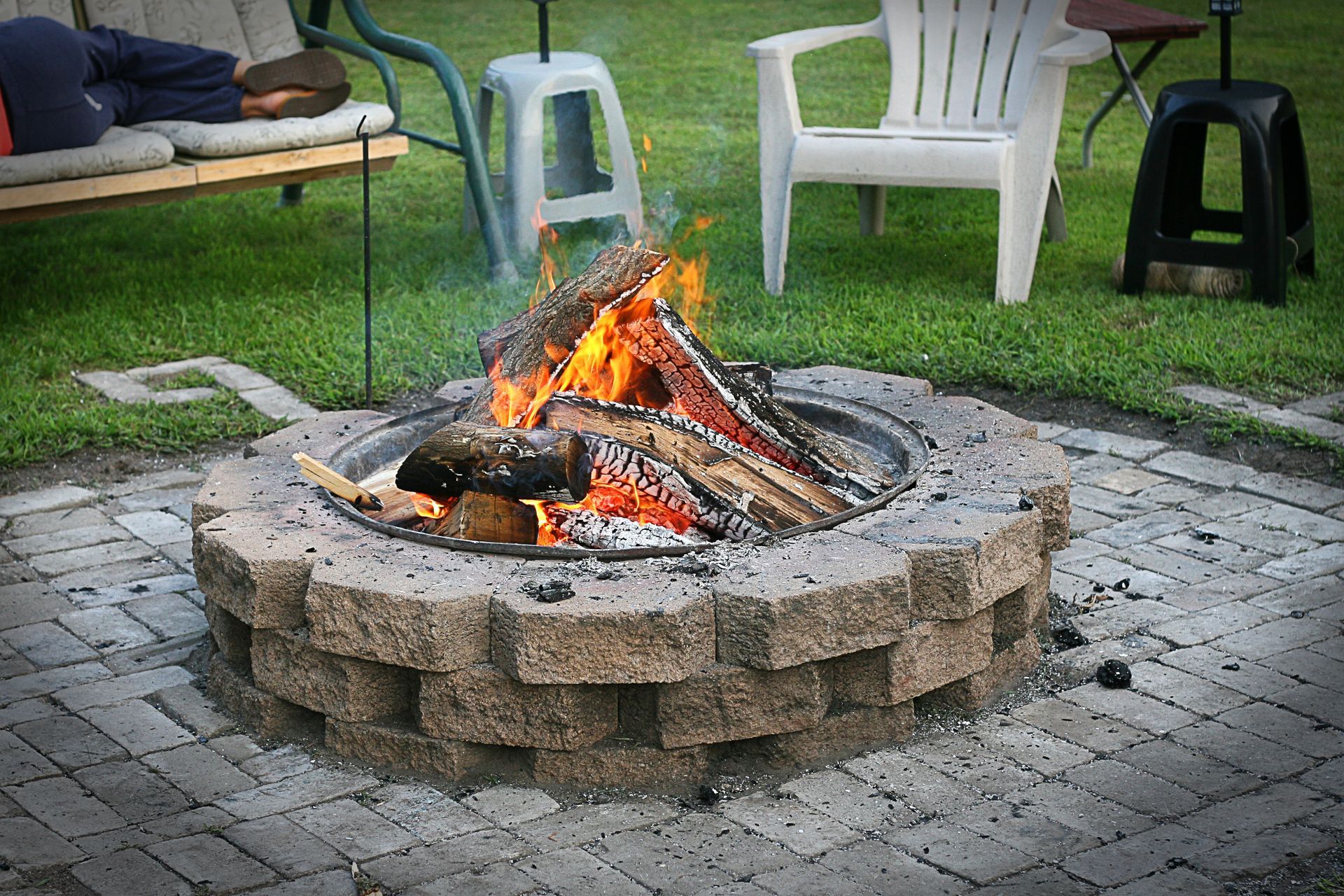 A fire pit is surrounded by chairs and a bench