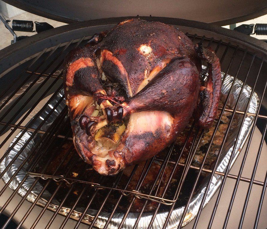 A large turkey is cooking on a grill