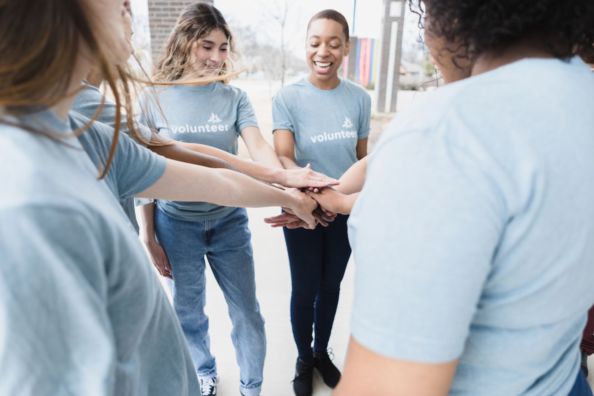 A group of volunteers are putting their hands together in a circle.