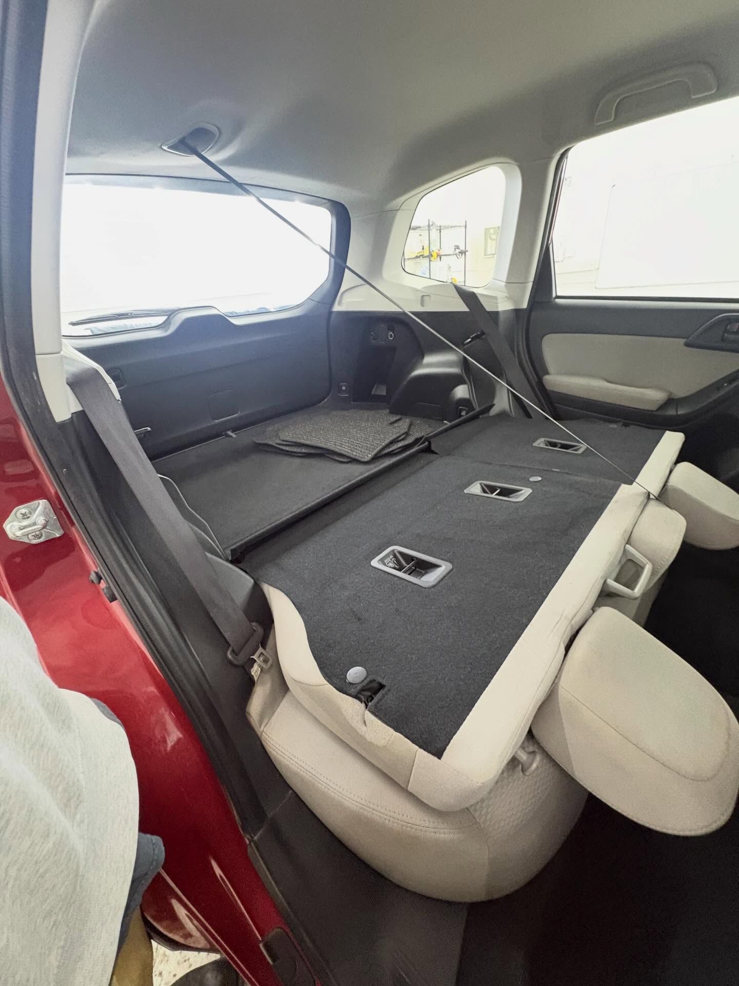 Interior view of a vehicle cargo area with beige rear seats folded flat to expand storage space.