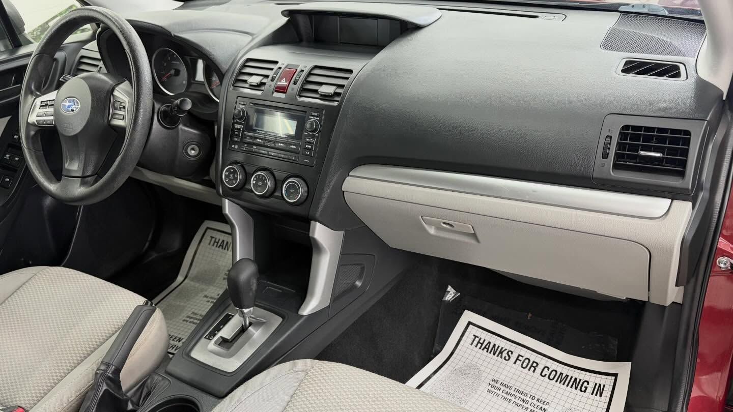 Interior view of a car cockpit featuring a black dashboard, light-colored fabric seats, and a gear shift.