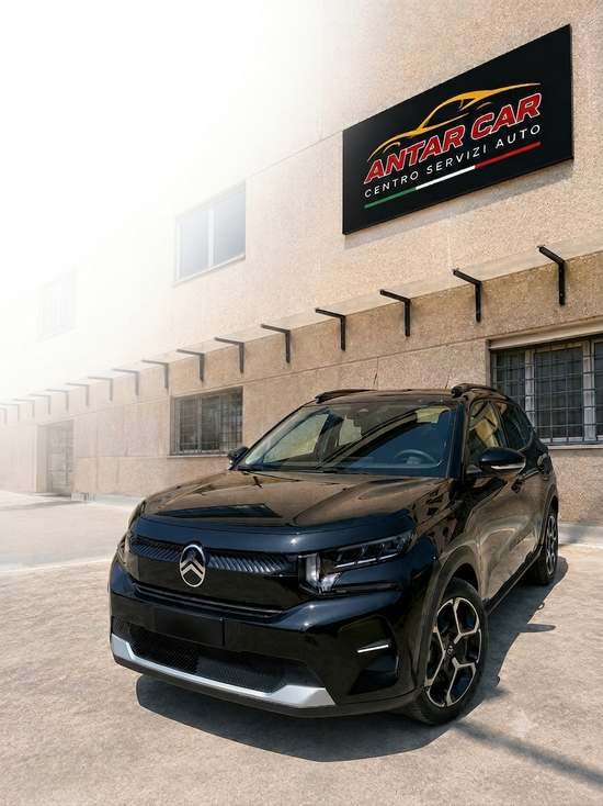 Un SUV Citroën nero è parcheggiato davanti a un edificio beige con un'insegna commerciale sopra.
