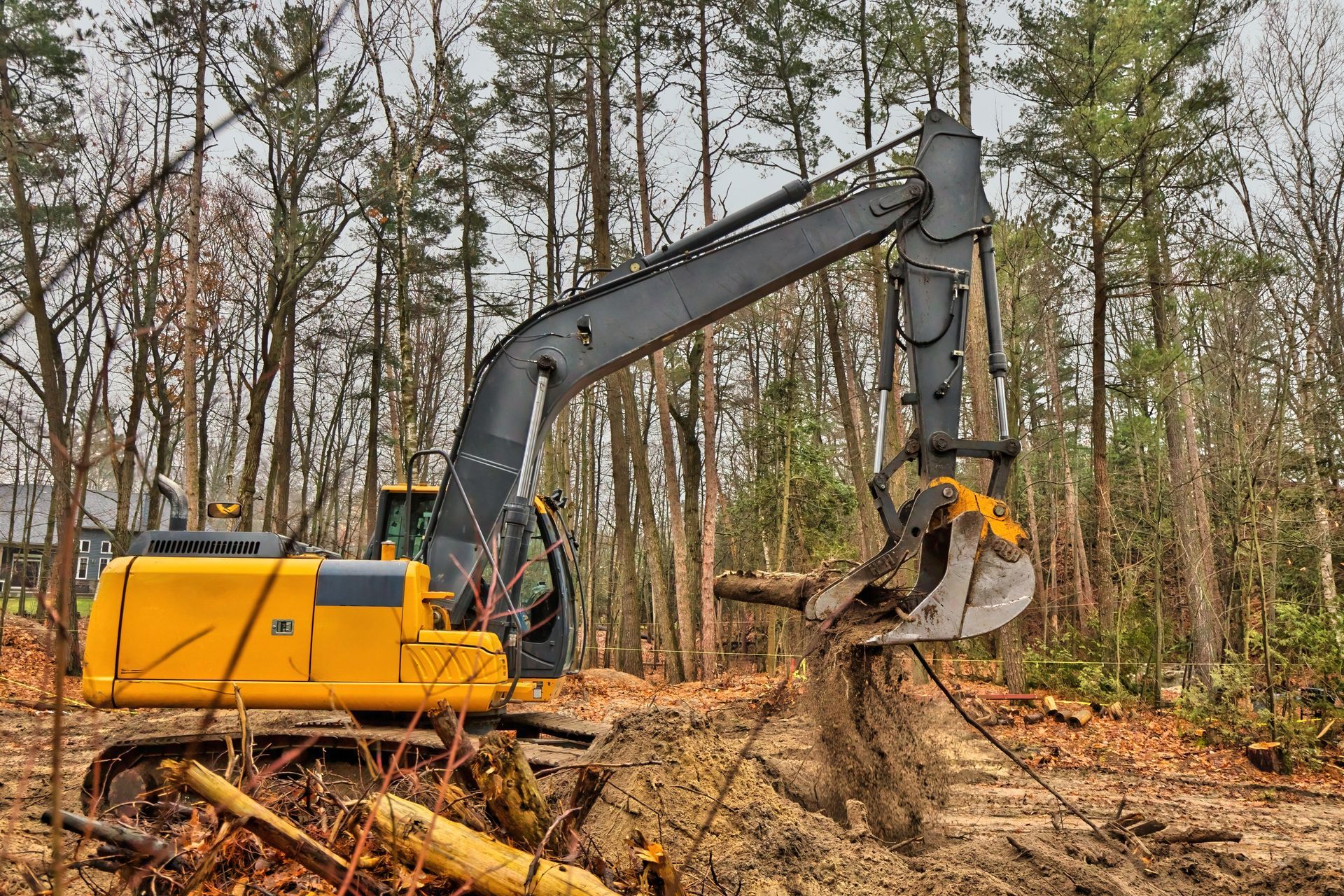 Yellow excavator in a wooded area, digging.
