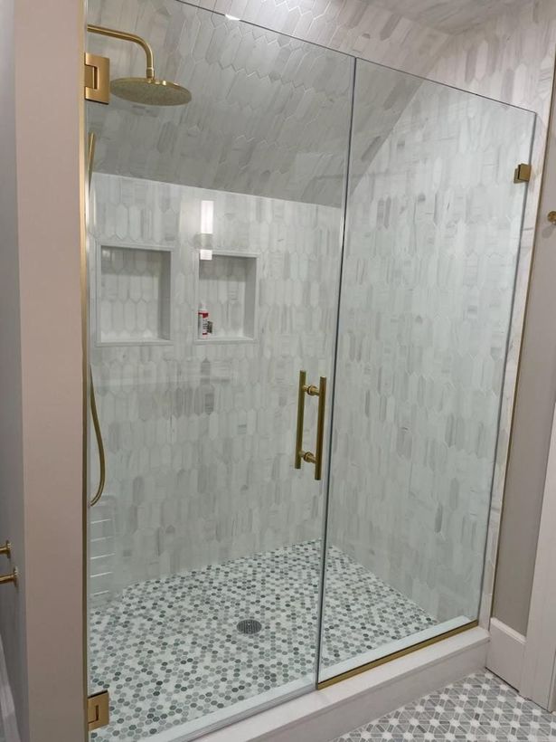 A bathroom with a walk in shower with a glass door and a shower head.