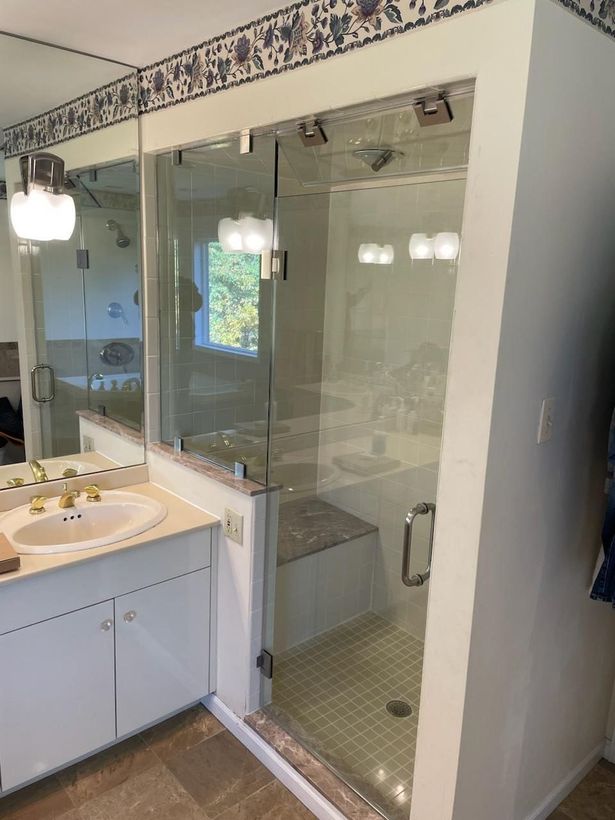A bathroom with a walk in shower , sink and mirror.
