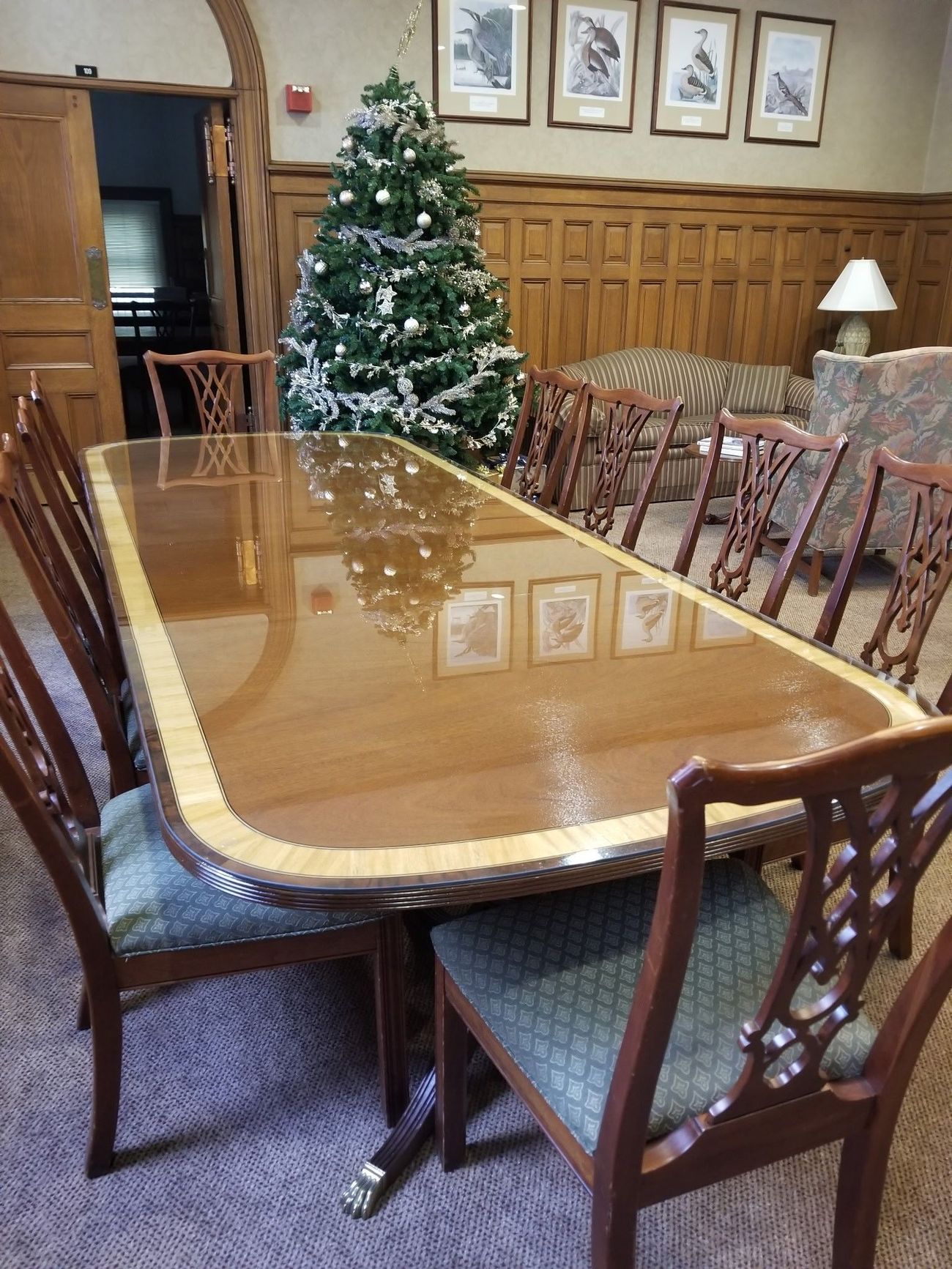 A long wooden table with chairs and a christmas tree in the background