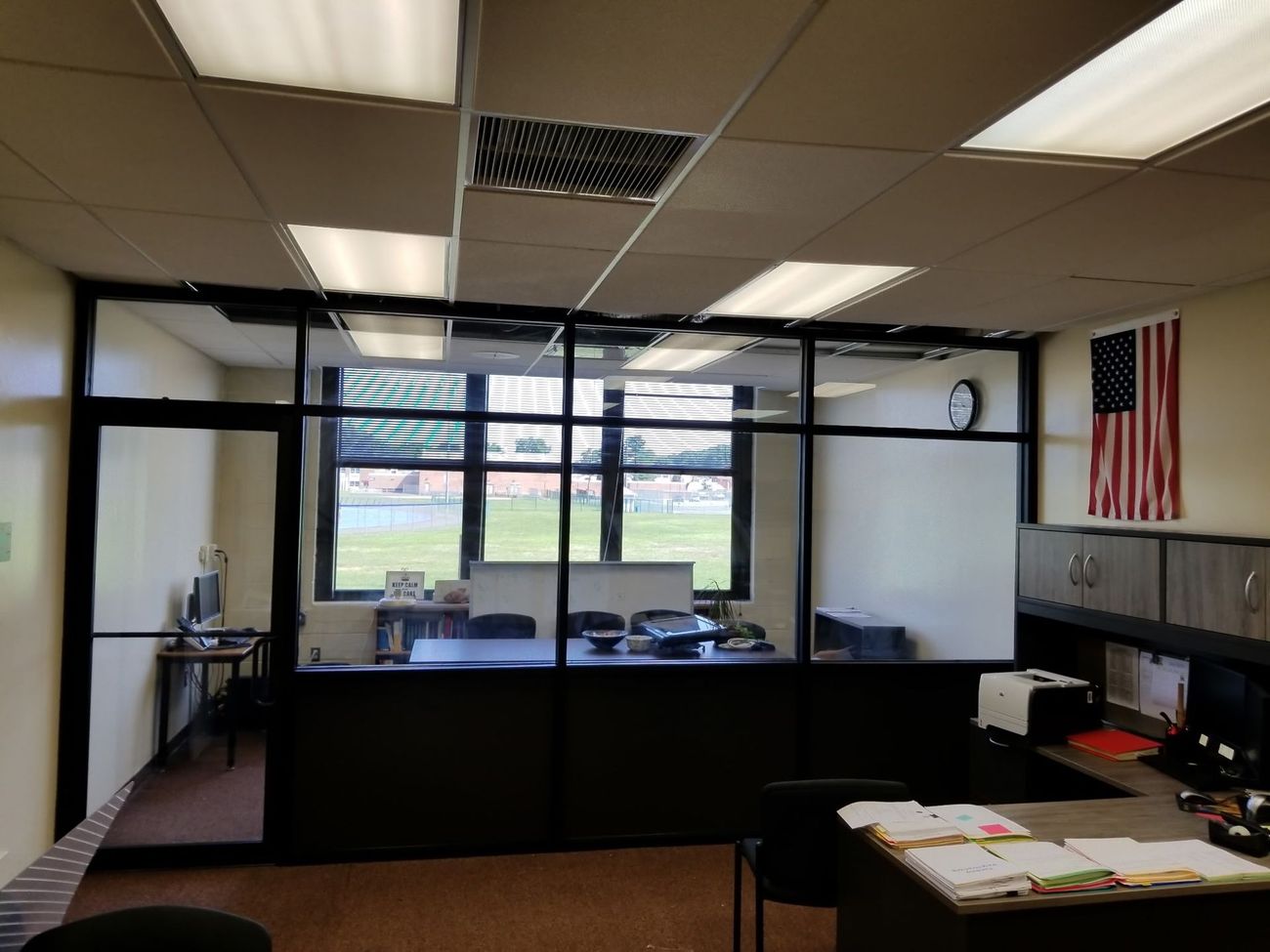 An office with a clock on the wall and a flag on the wall.