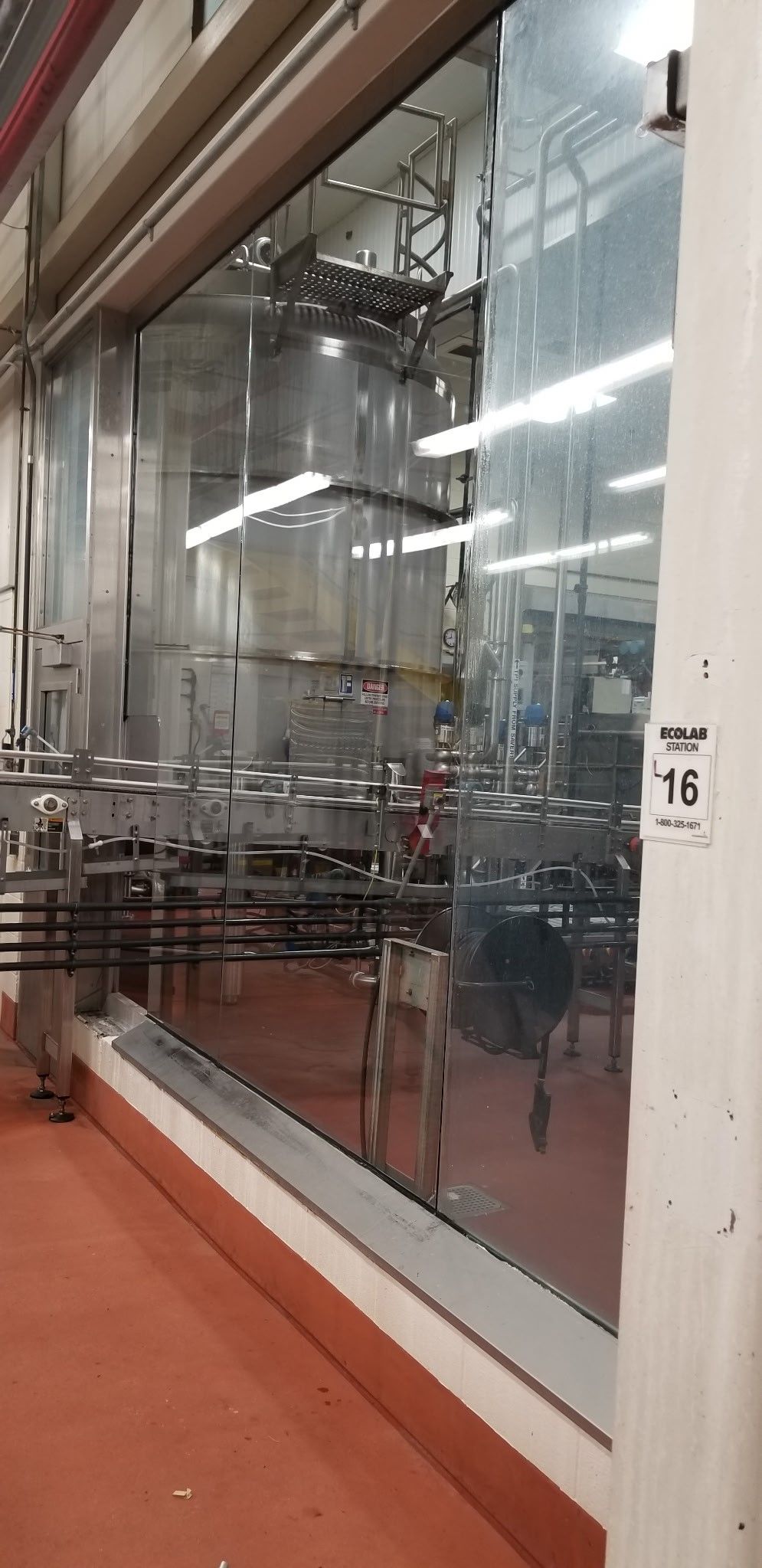 A large glass wall in a factory with a lot of machinery behind it.