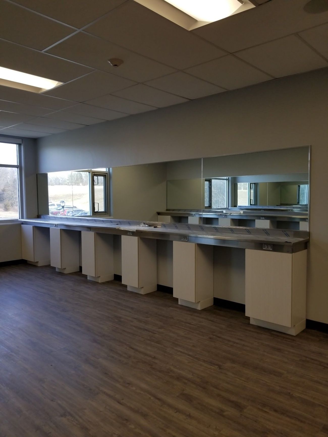 A room with a row of sinks and mirrors