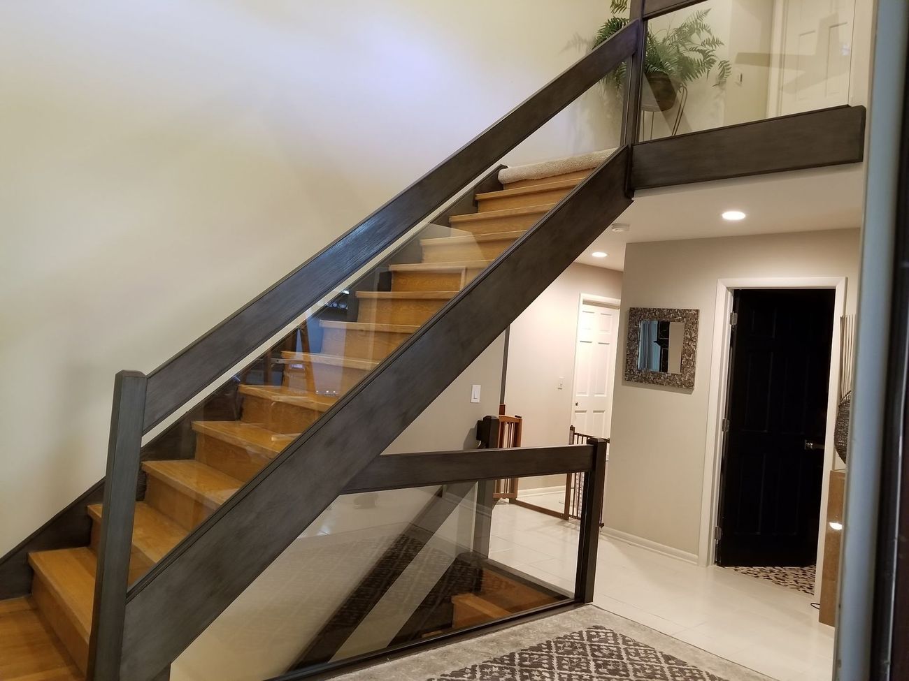 A wooden staircase with a glass railing in a house.