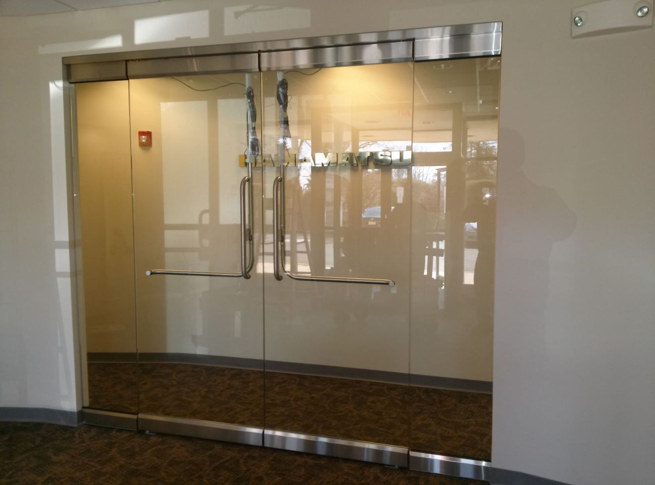 An empty room with a glass door and a fire extinguisher on the wall