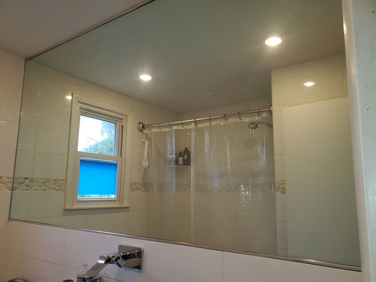 A bathroom with a large mirror and a shower curtain.