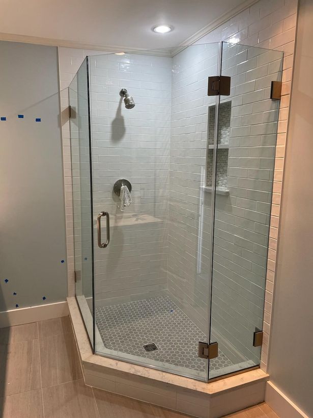 A bathroom with a walk in shower with a glass door.