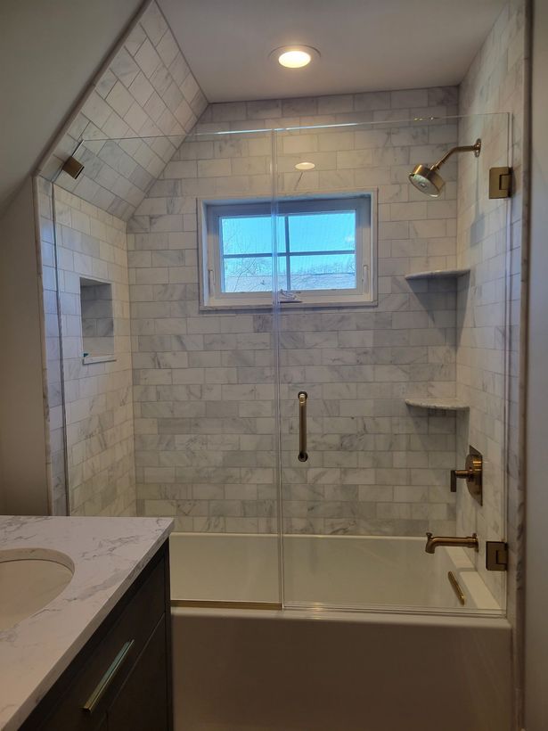A bathroom with a bathtub , sink , shower and window.