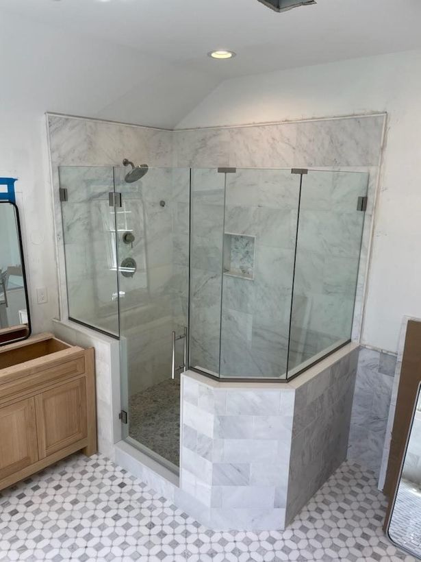 A bathroom with a walk in shower with a glass door.