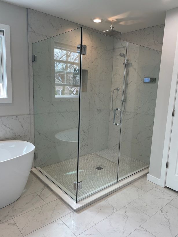 A bathroom with a walk in shower , tub , toilet and window.