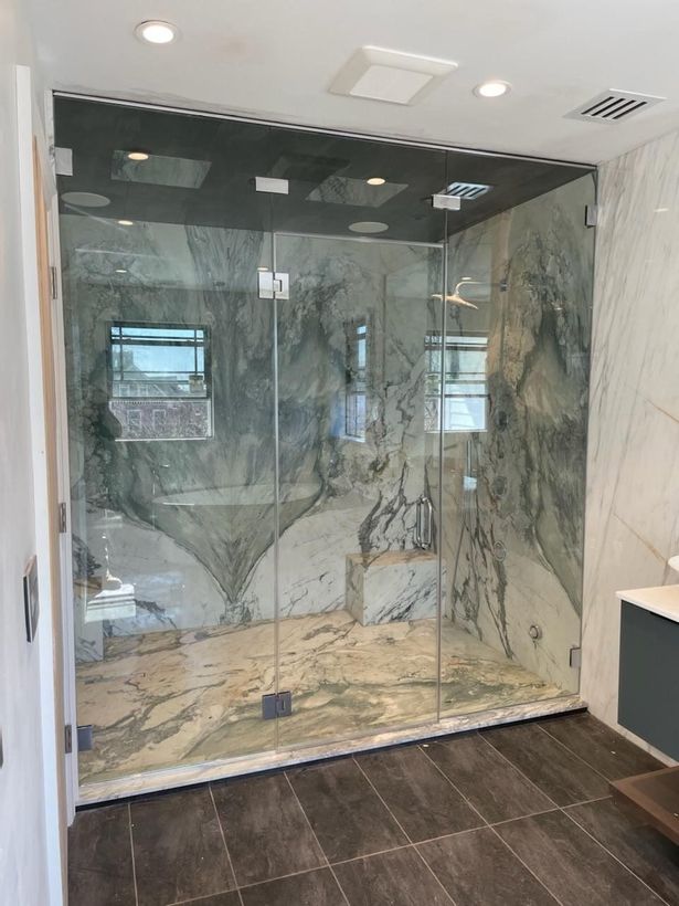 A bathroom with a walk in shower and a marble wall.