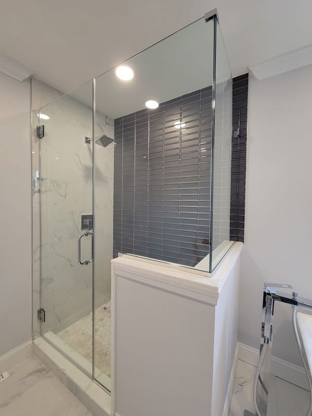 A bathroom with a walk in shower with a glass door.