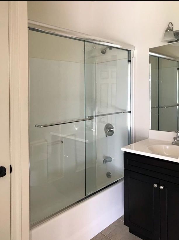 A bathroom with a glass shower door and a sink.
