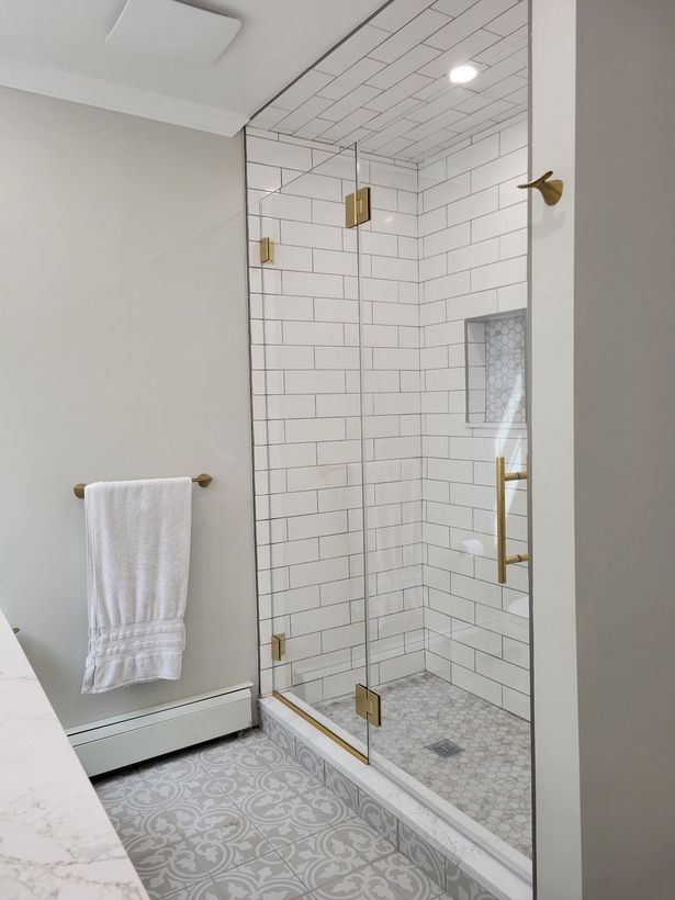 A bathroom with a walk in shower with a glass door.