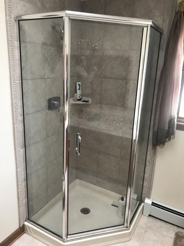 A bathroom with a shower stall and a window.