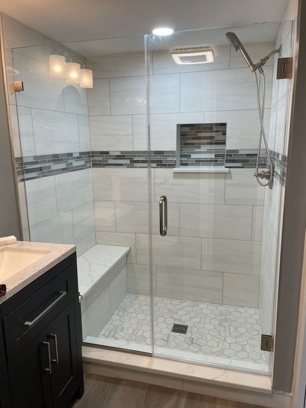 A bathroom with a walk in shower with a glass door.