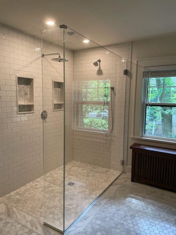 A bathroom with a walk in shower and a window.
