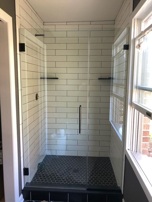 A shower with black and white tiles and a glass door
