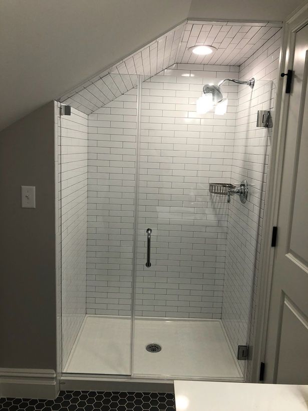 A bathroom with a walk in shower with a glass door.