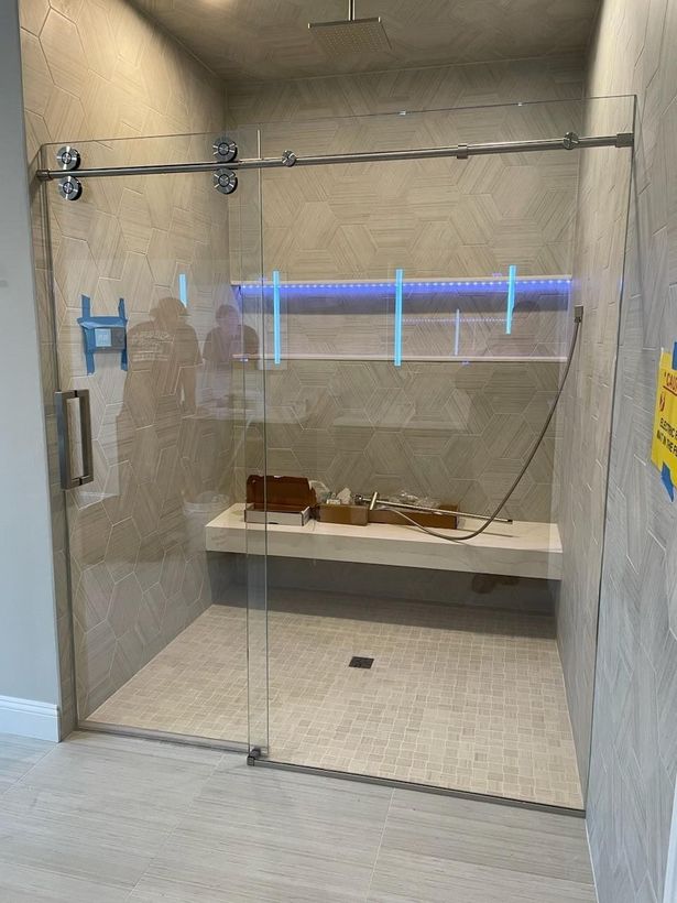 A bathroom with a sliding glass shower door and a bench.