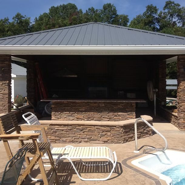 Covered patio with stone bar, metal roof, lounge chairs, and a hot tub.