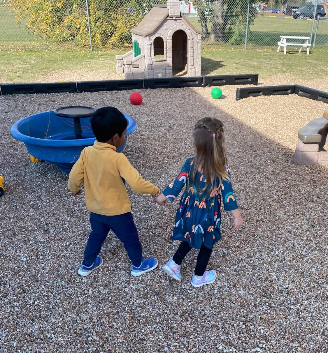 a boy and a girl are holding hands in a playground