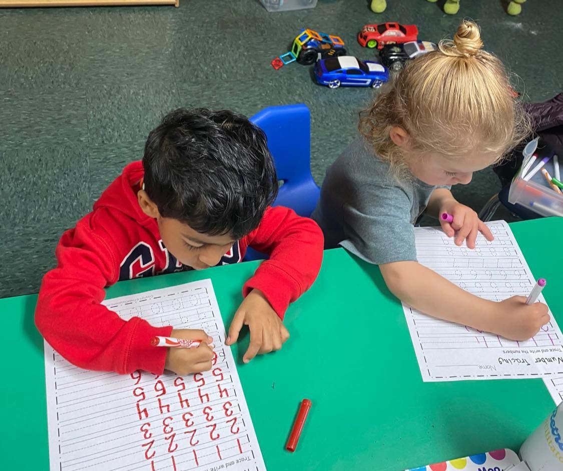 a boy and a girl are sitting at a table writing on a piece of paper