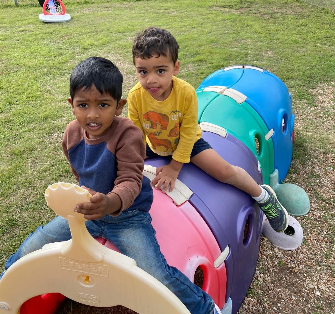 two young boys are sitting on a colorful toy train .