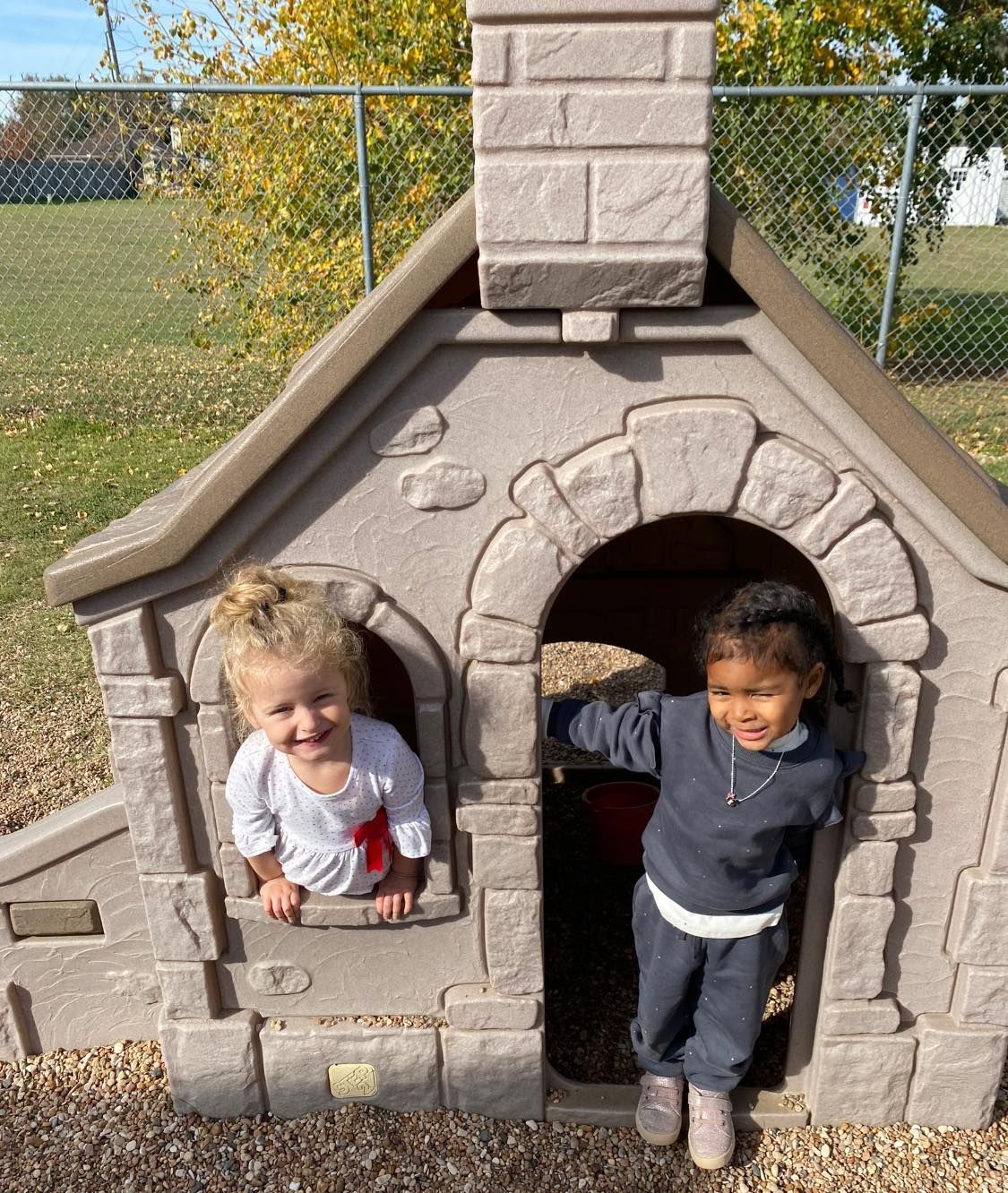 two children are playing in a playhouse in a park