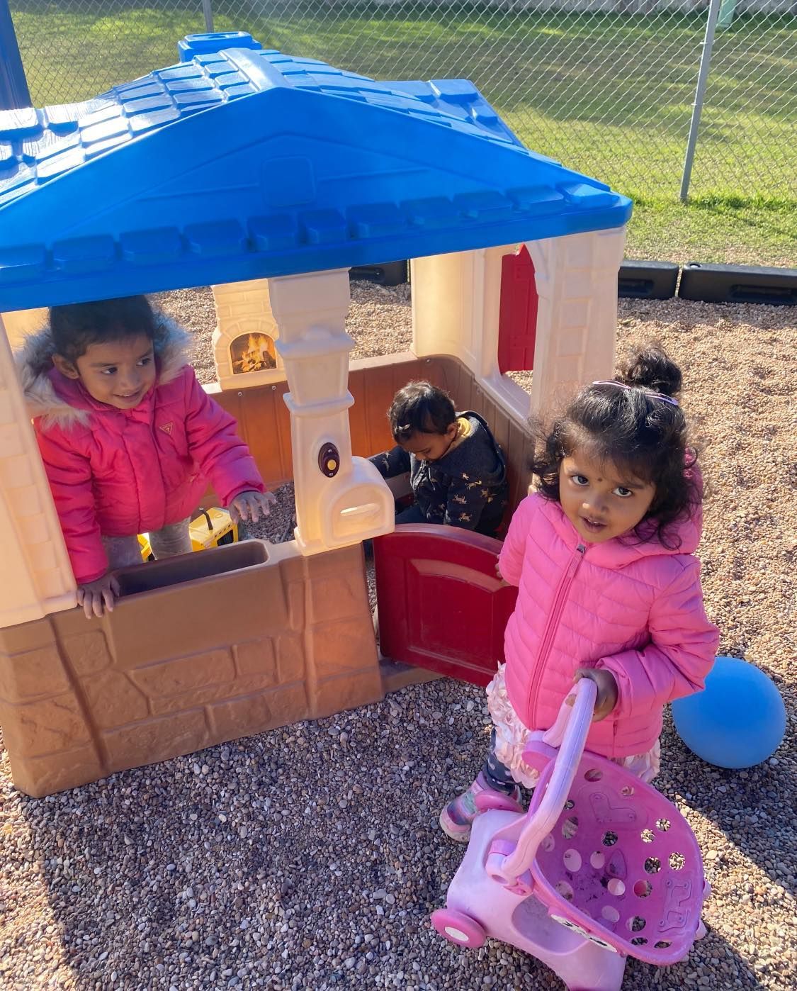 two little girls are playing in a playhouse in the sand .