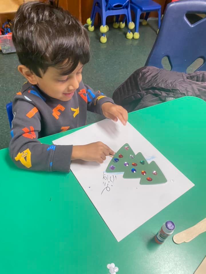 a young boy is sitting at a table decorating a christmas tree