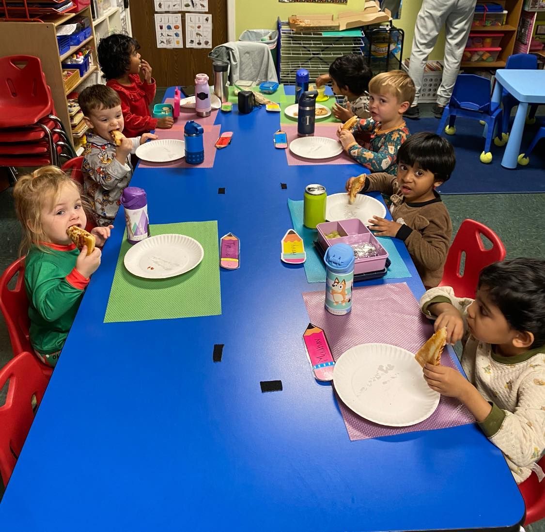 a group of children are sitting at a table eating food