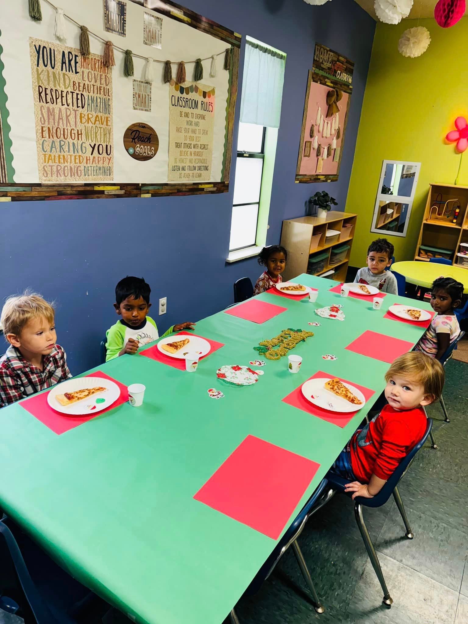 a group of children are sitting at a table with plates of food on it